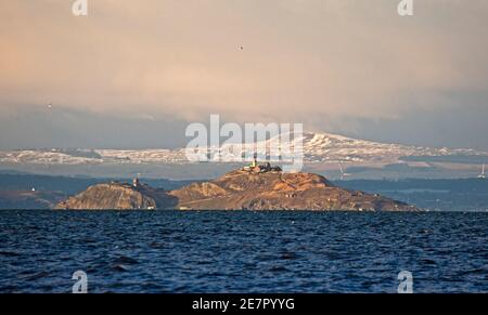 Portobello, Edimburgo, Scozia, Regno Unito. 30 gennaio 2021. Pomeriggio luminoso e freddo al mare affollato. Nella foto: Isola di Inchkeith con collina di Lomond coperta di neve alle spalle. Foto Stock