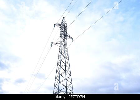 Torre elettrica a media tensione sulla montagna. Sfondo blu cielo con nuvole. Foto Stock