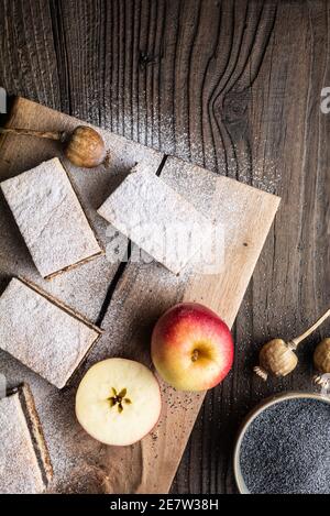 Deliziosa torta di pasta lievitata con semi di papavero e ripieno di mela, cosparsa di zucchero in polvere su rustico fondo di legno Foto Stock