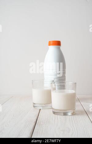 Due bicchieri pieni di latte e una bottiglia su fondo bianco. Foto Stock