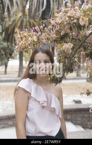 Ritratto di una giovane allegra donna che si pone dalla fioritura albero Foto Stock