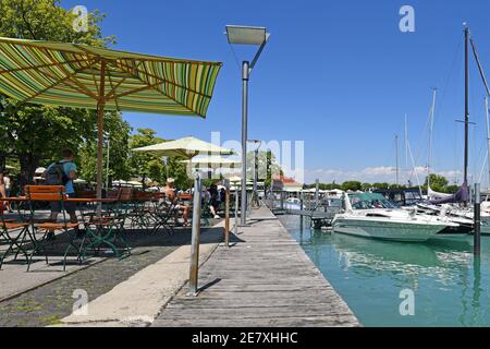 Konstanz, Germania - 2020 luglio: Caffè all'aperto con ombrelloni e barche a yacht marina al porto sul lago di Costanza in estate soleggiato giorno Foto Stock