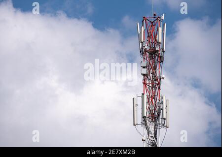 Un palo dell'antenna del telefono cellulare o del telefono cellulare contro un cielo nuvoloso e soleggiato Foto Stock