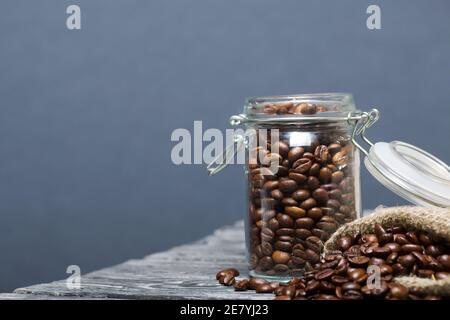 Chicchi di caffè. Versate in un vasetto di borsa di trascinamento e in una borsa di lino. Primo piano. Foto Stock