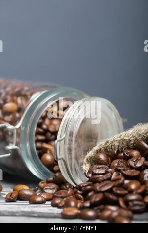 Chicchi di caffè. Versate in un vasetto di borsa di trascinamento e in una borsa di lino. La banca è ribaltata. Primo piano. Foto Stock