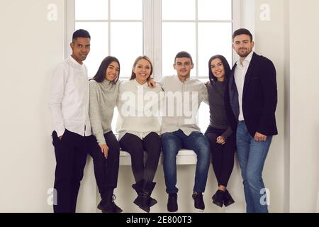Gruppo di giovani che sorridono diverse etnie seduti sul davanzale e abbracciando Foto Stock