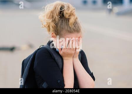 Ragazza seduta piangendo dopo che è caduto mentre cavalcava il suo scooter sulla strada della città Foto Stock