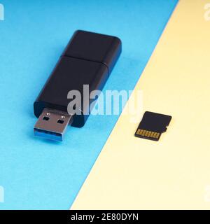 chiavetta usb e scheda di memoria micro sd su sfondo blu e giallo. diversi tipi di dispositivi di archiviazione portatili. concetto di archiviazione dei dati Foto Stock