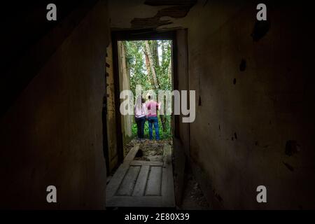 coppia lasciando casa in rovina per esplorare la natura Foto Stock