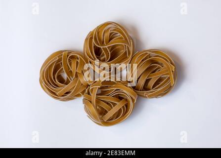 Pasta bruna grezza integrale Tagliatelle su fondo bianco, fatta con farina di grano, ricca di nutrienti: Proteine, carboidrati e fibre Foto Stock