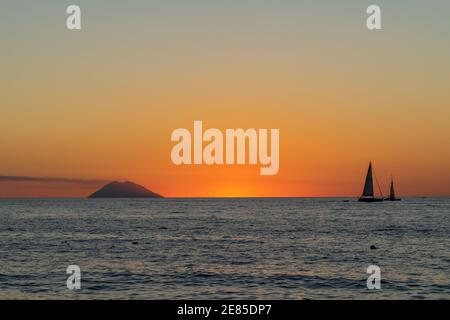 Bellissimo tramonto sul Mar Tirreno e l'isola di Stromboli con una barca a vela vista da Tropea, Calabria, Italia Foto Stock