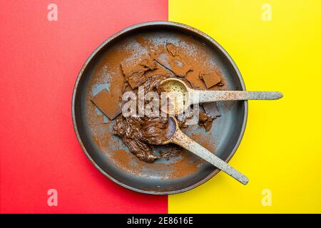 crema di cacao alle nocciole e pezzi di cioccolato mescolati in una ciotola su sfondo giallo e rosso. vista dall'alto Foto Stock