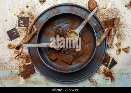 crema di cacao alle nocciole e pezzi di cioccolato mescolati in una ciotola su uno sfondo di legno chiaro. vista dall'alto Foto Stock