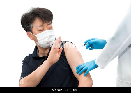 Uomo asiatico di mezza età che indossa una maschera medica che rifiuta di iniettare il vaccino. Foto Stock