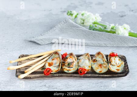 Porzione di cozze cotte al forno con parmigiano su piatto rettangolare Foto Stock