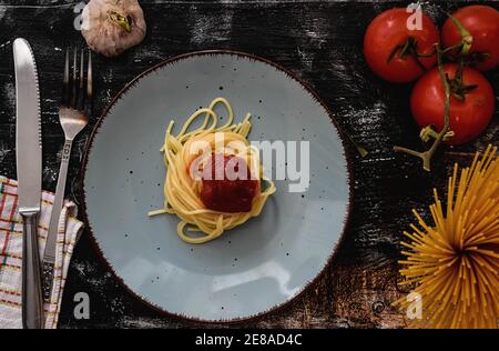 Spaghetti alla bolognese e salsa di pomodoro serviti con aglio e pomodori su vecchio sfondo rustico Foto Stock