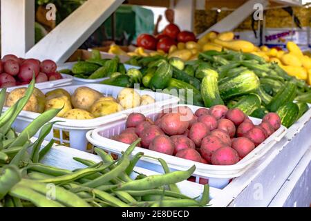 Fagioli verdi, patate, cetrioli e zucca gialla esposti presso un mercato agricolo Foto Stock