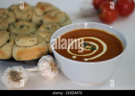 Zuppa di pomodoro sana fatta in casa abbinata a una cena appena sfornata Panini con burro di aglio e erbe italiane Foto Stock