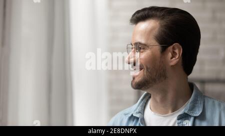 Primo piano uomo sorridente e sognante che indossa occhiali che guardano da parte Foto Stock