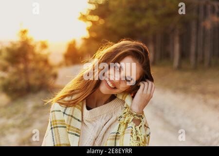 Donna felice ha inclinato la testa al lato in natura vicino alberi di conifere nella foresta Foto Stock