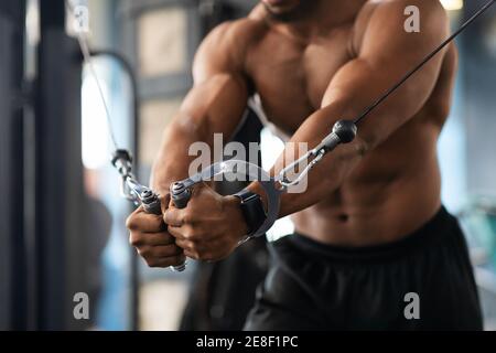 Cropped di addestramento del ragazzo nero sul blocco exerciser in palestra Foto Stock