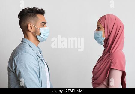 Concetto di allontanamento sociale. Profilo Tiro di coppia musulmana in maschere mediche protettive Foto Stock