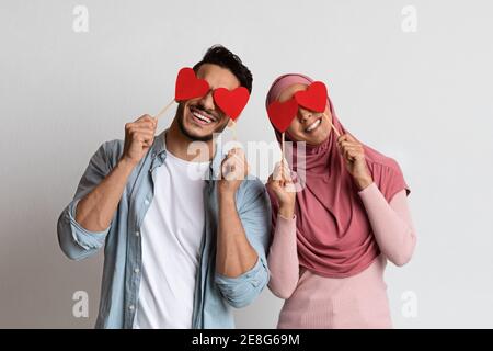 Divertimento di San Valentino. Allegro uomo musulmano e Donna che copre gli occhi con cuori rossi Foto Stock