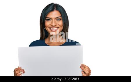 Giovane donna transessuale latina che tiene vuoto banner cercando positivo e felice in piedi e sorridente con un sorriso fiducioso visualizzazione di te Foto Stock