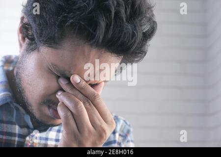 Primo piano di uomo sconvolto che soffre di forte dolore agli occhi Foto Stock