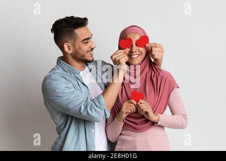 Allegra coppia musulmana divertirsi insieme il giorno di San Valentino, tenendo cuori rossi Foto Stock