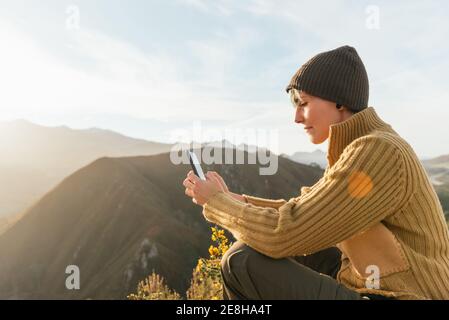 Divertente giovane artista mimo femminile con trucco brillante in costume bianco chef pouting labbra mentre si prende selfie su smartphone con fresco grande porro in mano Foto Stock