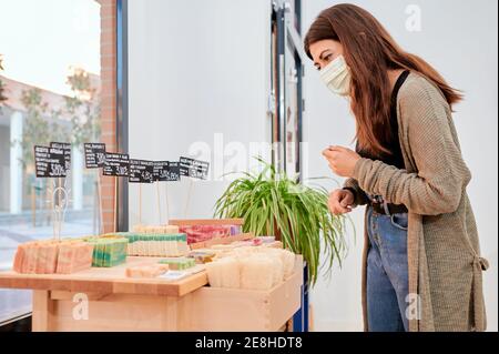 Attraente turista asiatico femminile in piedi su scala vicino al muro mentre osserva i vari fiori in vaso nella città di Cordoba in Spagna Foto Stock