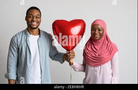 Felice coppia nera che tiene il pallone d'amore insieme Foto Stock