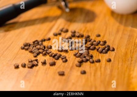 Chicchi di caffè e portafiltri posti su un tavolo di legno con vuoto tazza nel caffè Foto Stock