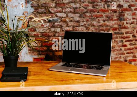 Netbook moderno collocato su bancone di legno in una caffetteria con interni in stile loft Foto Stock