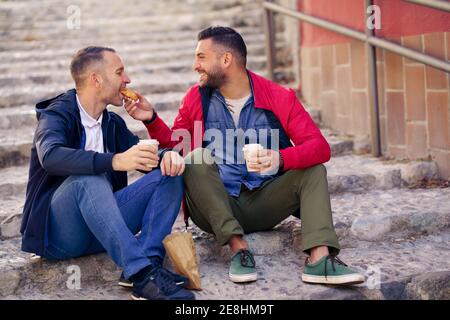 Una coppia gay che ha un pasto da portare via sulla strada Foto Stock