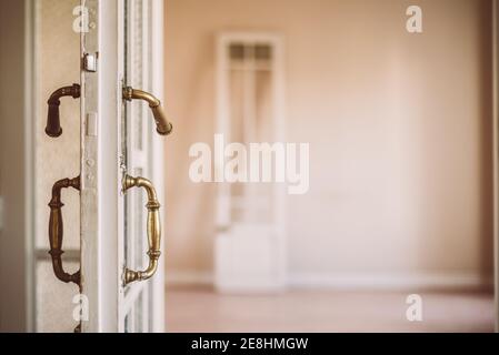 Porta aperta in legno bianco vecchio stile con maniglie ornamentali stile retrò in appartamento vuoto Foto Stock