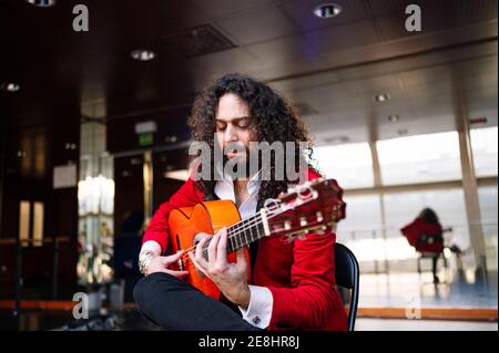 Musicista maschile focalizzato seduto sulla sedia e suonando la chitarra durante prova sul palco Foto Stock