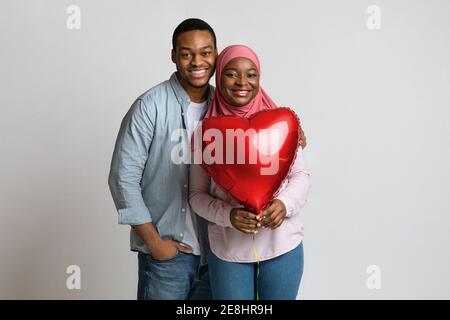 Gli amanti che tengono il palloncino a forma di cuore rosso e abbracciano Foto Stock
