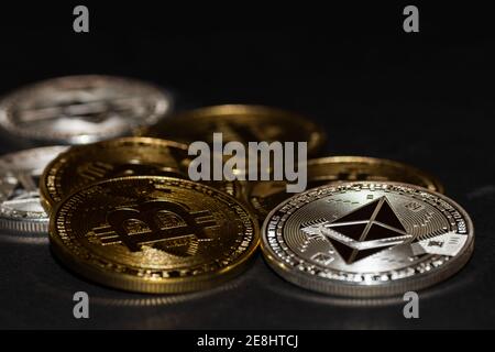 monete d'oro bitcoin e d'argento etere da criptovaluta su nero vista macro Foto Stock