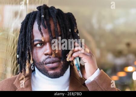 Serio hipster nero maschio con Dreadlock che parla sullo smartphone la strada Foto Stock