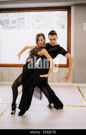 Coppia di ballerini di talento che si muovono con grazia mentre provano la danza da ballo in sala durante la lezione Foto Stock