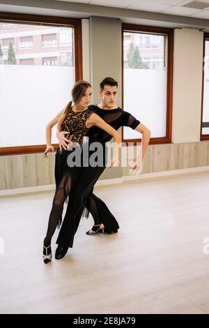 Coppia di ballerini di talento che si muovono con grazia mentre provano la danza da ballo in sala durante la lezione Foto Stock