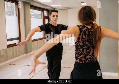Coppia di ballerini di talento che si muovono con grazia mentre provano la danza da ballo in sala durante la lezione Foto Stock