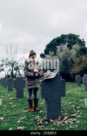 Piccolo capretto che piangono la morte del soldato che combatte in guerra a. cimitero Foto Stock