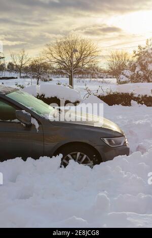 Vista laterale di coperta con auto grigio neve in città alla luce del sole Foto Stock