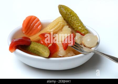 Impastare sottaceti con carote, cavolfiori, cetrioli, cipolle e mais sulla pannocchia in un recipiente con forchetta, sottaceto, sottaceto Foto Stock