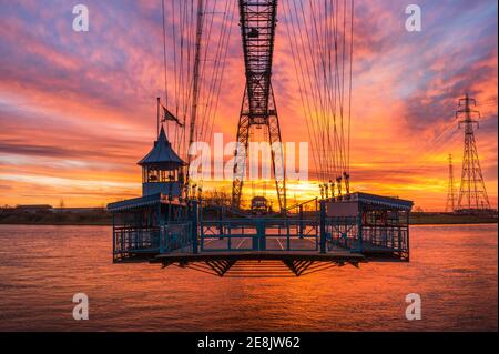 Il sole sorge dietro la funivia del Newport Transporter Bridge Foto Stock