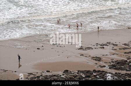 Swansea, Regno Unito. 31 gennaio 2021. Un surfista guarda un gruppo di nuotatori sfidare il mare freddo a Langland Bay, Swansea questa mattina, mentre la neve è caduta su gran parte del Galles del Sud. Credit: Phil Rees/Alamy Live News Foto Stock