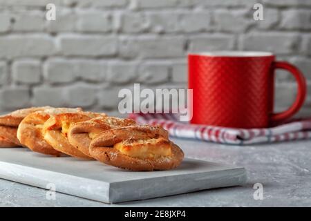 Cottura fatta in casa, biscotti fatti in casa con formaggio casereccio e una tazza di tè rosso su sfondo grigio Foto Stock